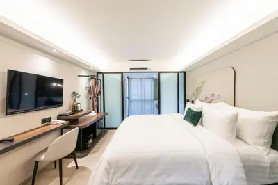 a hotel room with a large white bed and a desk at Kaya Heritage Hotel in Bangkok