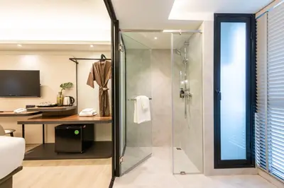 a glass shower in a bathroom with a desk at Kaya Heritage Hotel in Bangkok