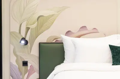 a bedroom with a bed with a flower mural on the wall at Kaya Heritage Hotel in Bangkok