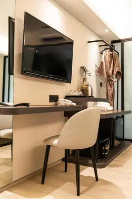 a desk with a chair and a television on a wall at Kaya Heritage Hotel in Bangkok