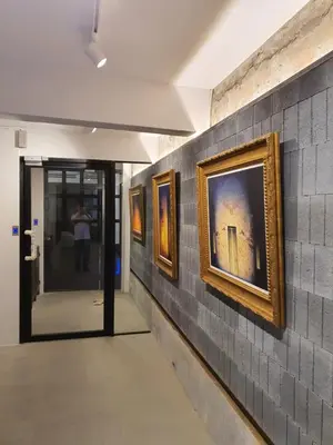 a hallway with three paintings on a wall at Roompini in Bangkok