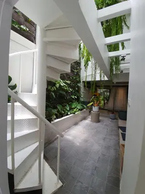 a hallway with stairs and plants in a building at Roompini in Bangkok