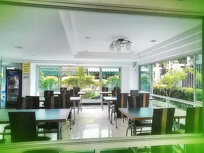 a dining room with tables and chairs and windows at THE PRIZE in Ban Yang