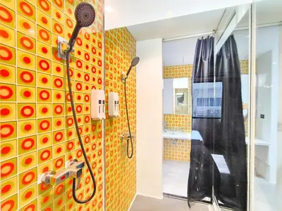 a shower in a bathroom with a yellow tile wall at Citin Sukhumvit 11 Nana Bangkok by Compass Hospitality in Bangkok