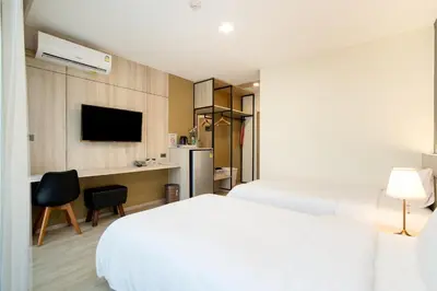 a hotel room with two beds and a desk at Amanah Bangkok Hotel in Bangkok