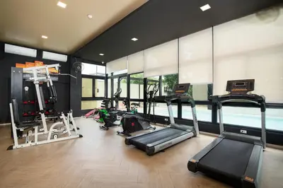 a gym with cardio equipment and a swimming pool at Amanah Bangkok Hotel in Bangkok