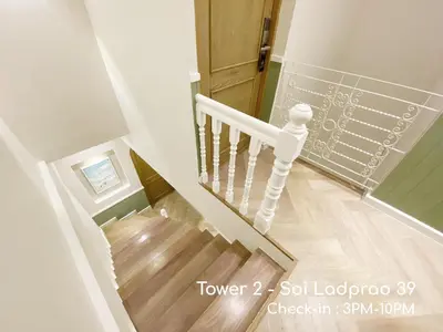a staircase with a white rail and a wooden door at Double Bed Hotel in Bangkok