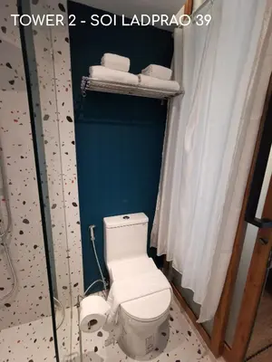 a bathroom with a white toilet and some towels at Double Bed Hotel in Bangkok