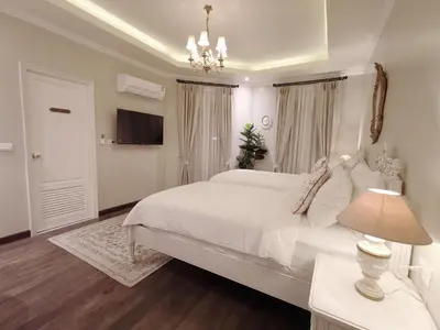 a white bedroom with a large bed and a chandelier at Double Bed Hotel in Bangkok