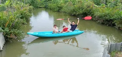 two people in a blue kayak on a river at BaanSuanklaiKlungBangkrachao บ้านสวนใกล้กรุงบางกะเจ้า in Phra Pradaeng