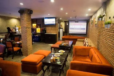 a restaurant with orange furniture and a bar with a screen at Arawana Residence Phromphong in Bangkok