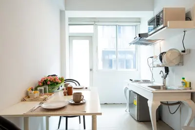 a white kitchen with a sink and a table at Arawana Residence Phromphong in Bangkok