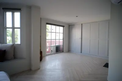 an empty room with white walls and a large window at Baan Khun Pra Duplex Rm3 Bangkok in Bangkok