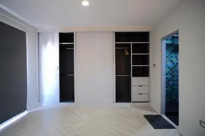 a room with a closet with white walls and wood floors at Baan Khun Pra Duplex Rm3 Bangkok in Bangkok