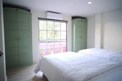 a bedroom with two beds and a window at Baan Khun Pra Duplex Rm3 Bangkok in Bangkok