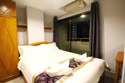 a hotel room with a bed with white towels on it at Lee Place Phatthanakan Condo in Bangkok