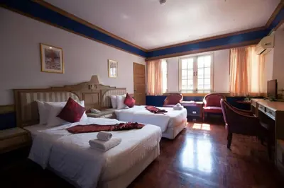 a hotel room with two beds and a desk at Suda Palace in Bangkok