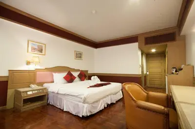 a hotel room with a bed and a chair at Suda Palace in Bangkok