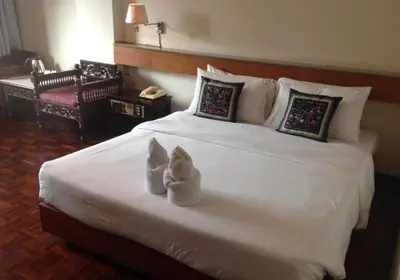 a bedroom with a white bed with two shoes on it at Suda Palace in Bangkok