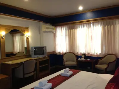 a hotel room with a bed and a desk and a television at Suda Palace in Bangkok