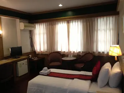 a hotel room with a bed and a chair and a window at Suda Palace in Bangkok