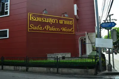 a sign on the side of a red building at Suda Palace in Bangkok