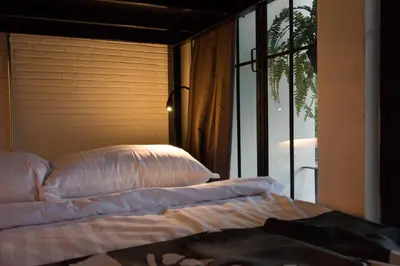 a bed with pillows in a room with a window at Hidden Habitat - Design Guesthouse in Bangkok