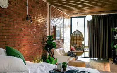 a brick walled bedroom with a bed and a chair at Hidden Habitat - Design Guesthouse in Bangkok