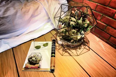a book and a pen on a table with a plant at Hidden Habitat - Design Guesthouse in Bangkok