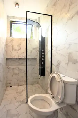 a white bathroom with a toilet and a shower at Hidden Habitat - Design Guesthouse in Bangkok