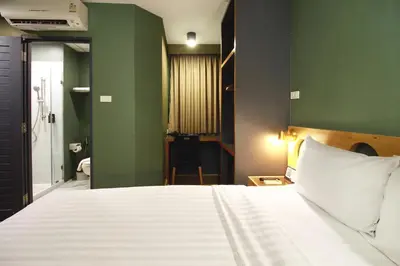 a bedroom with a white bed and a green wall at MyBed Ratchada in Bangkok