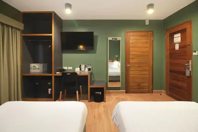 a hotel room with two beds and a desk and a mirror at MyBed Ratchada in Bangkok