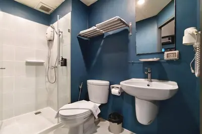 a blue bathroom with a toilet and a sink at MyBed Ratchada in Bangkok