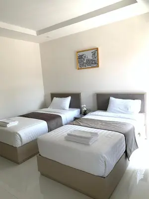 two beds in a room with white walls at Icare Residence & Hotel in Bangkok