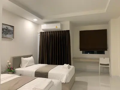 a hotel room with two beds and a flat screen tv at Icare Residence & Hotel in Bangkok