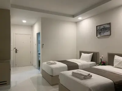 a bedroom with two beds and a door to a bathroom at Icare Residence & Hotel in Bangkok