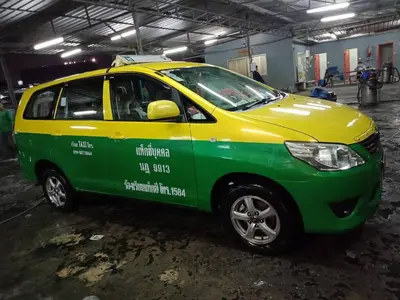 a small green and yellow car parked in a garage at Airport Transfer Bangkok apartment in Thung Si Kan