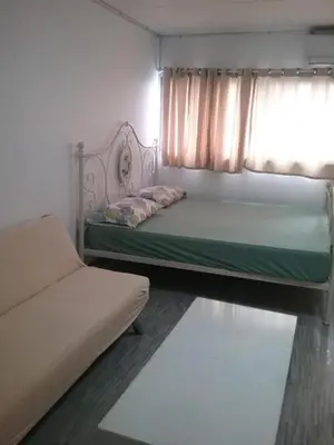a bedroom with a bed and a window and a couch at Thailand Taxiapartment Hostel in Thung Si Kan
