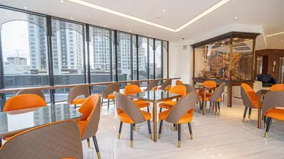 a restaurant with orange chairs and tables and windows at Pannarai Hotel Bangkok-Pra tunam in Bangkok