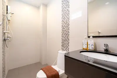 a bathroom with a sink and a toilet and a mirror at LeeNova Place in Lat Krabang