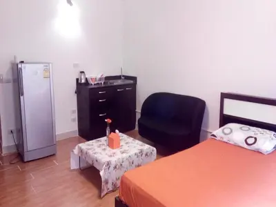 a room with a refrigerator and a chair and a table at Asia Don Mueang Bangkok Condominium in Thung Si Kan