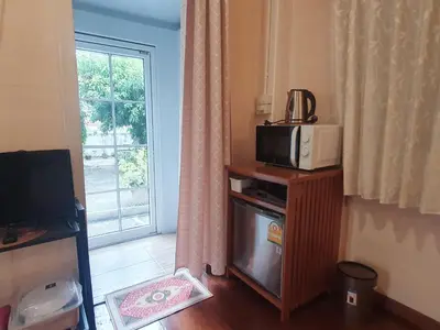 a microwave on top of a wooden stand with a window at KINN Stay50 Bangkok in Bangkok Yai