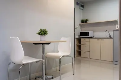 a kitchen with a table and two white chairs at LKN RESIDENCE in Pom Prap