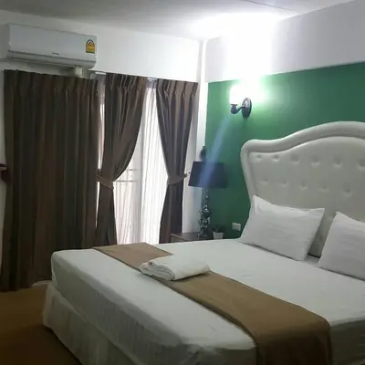 a bedroom with a large bed with a green wall at I-Inn Hotel in Bangkok