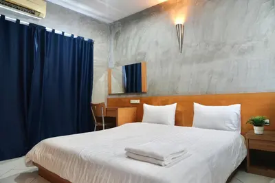 a bedroom with a large white bed with blue curtains at The View Residence in Bangkok