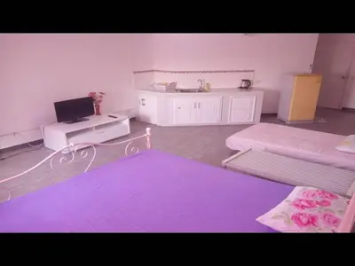 a room with two beds and a desk with a laptop at Impact Don Mueang Bangkok Guest House in Thung Si Kan