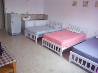 a room with three beds and a kitchen with a refrigerator at Impact Thunder Dome Service Taxi in Thung Si Kan