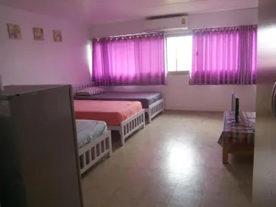 a bedroom with two beds and a window with pink curtains at Thailand Taxiapartment Hostel in Thung Si Kan