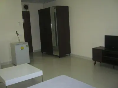 a living room with a refrigerator and a table at Chan Kim Don Mueang Guest House Triple room in Thung Si Kan