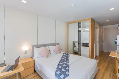 a bedroom with a bed and a laptop on a desk at United Residence Ekamai Bangkok in Bangkok